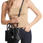 Woman holding a black handbag with a visible brand logo against a white background
